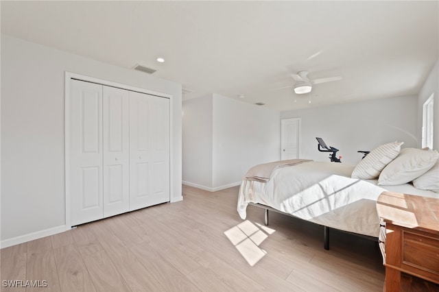 bedroom featuring visible vents, a closet, light wood-style floors, baseboards, and ceiling fan