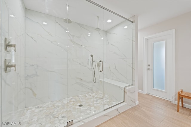 full bath featuring a marble finish shower, baseboards, and wood finished floors