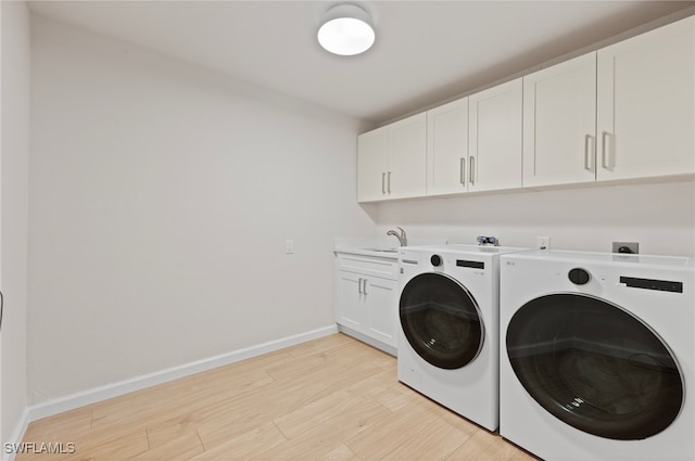 laundry room featuring baseboards, light wood-style flooring, cabinet space, a sink, and independent washer and dryer