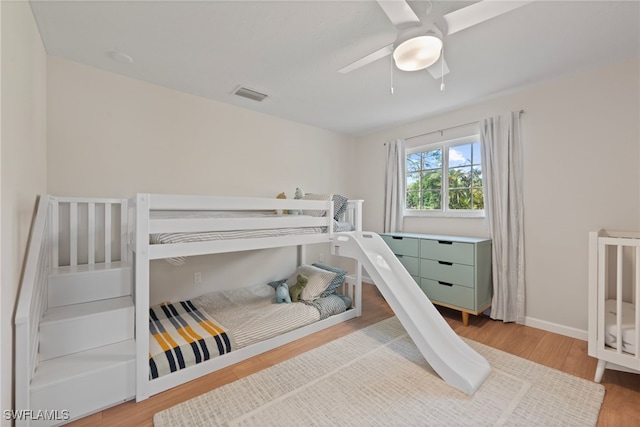 bedroom featuring ceiling fan, visible vents, baseboards, and wood finished floors