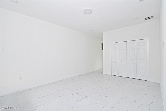 unfurnished bedroom with visible vents, marble finish floor, a closet, and baseboards