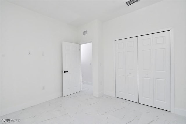 unfurnished bedroom with visible vents, marble finish floor, a closet, and baseboards