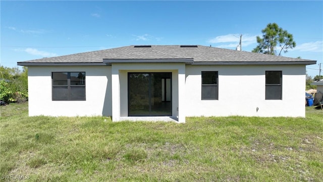 rear view of house featuring a lawn, roof with shingles, and stucco siding