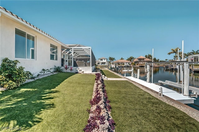 view of yard featuring boat lift, glass enclosure, a boat dock, and a water view