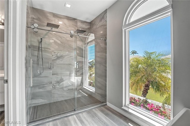 full bath with wood finished floors, baseboards, and a marble finish shower