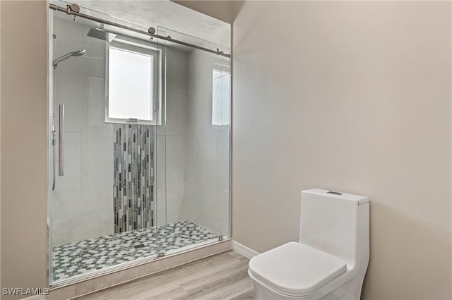 bathroom with a shower stall, toilet, baseboards, and wood finished floors