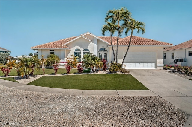 mediterranean / spanish house featuring a tile roof, concrete driveway, a front yard, stucco siding, and an attached garage