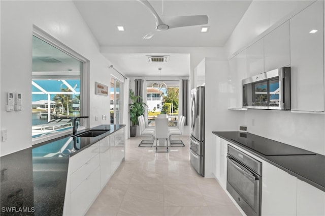 kitchen with black appliances, a sink, white cabinetry, and modern cabinets