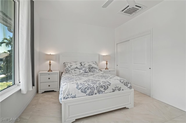 bedroom with light marble finish floors, a closet, baseboards, and ceiling fan