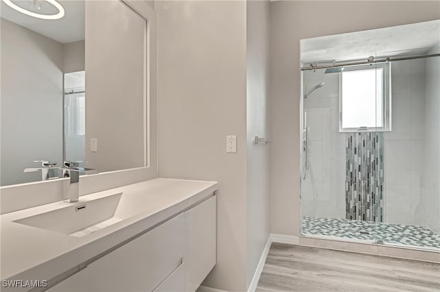 bathroom featuring a shower stall, wood finished floors, baseboards, and vanity