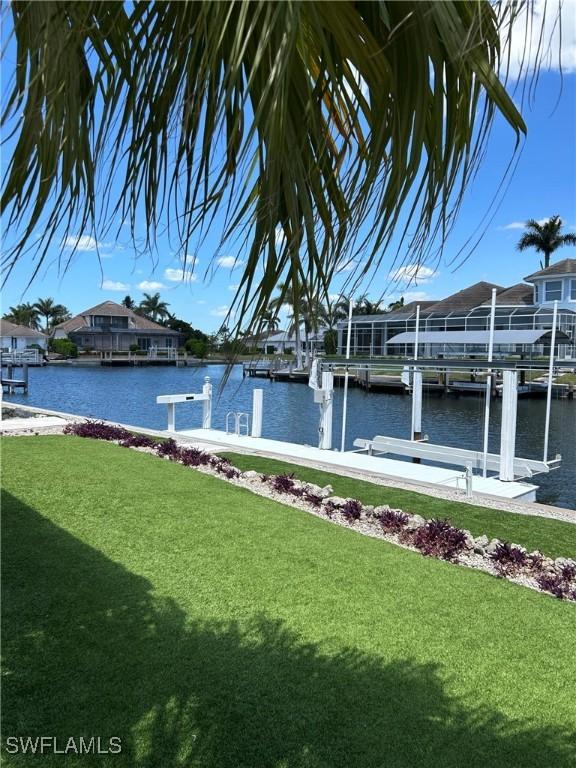 dock area featuring boat lift, a yard, a water view, and a residential view
