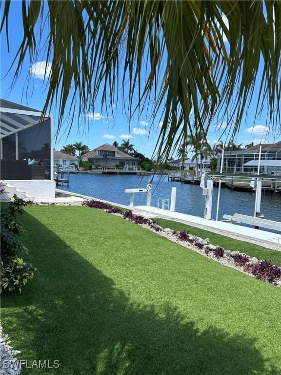 view of green lawn featuring a water view, a dock, and glass enclosure