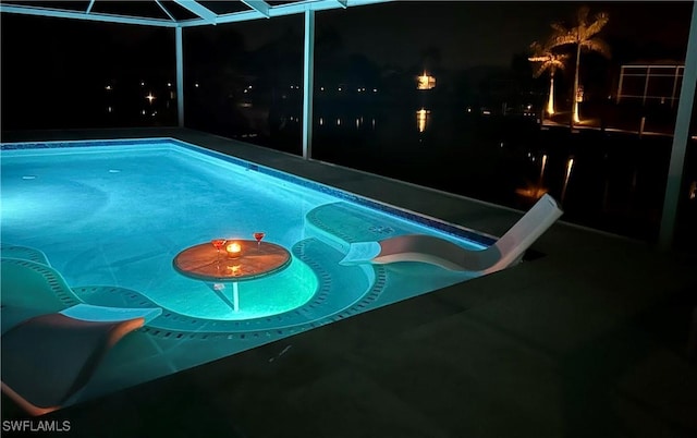 pool at twilight with an outdoor pool, a lanai, and a water slide