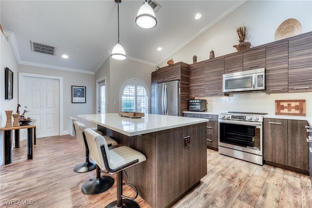 kitchen with visible vents, a kitchen island, stainless steel appliances, vaulted ceiling, and a kitchen breakfast bar