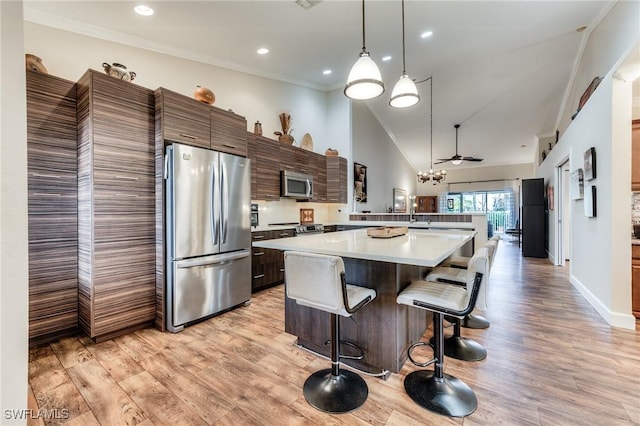 kitchen featuring light wood finished floors, appliances with stainless steel finishes, a peninsula, and light countertops