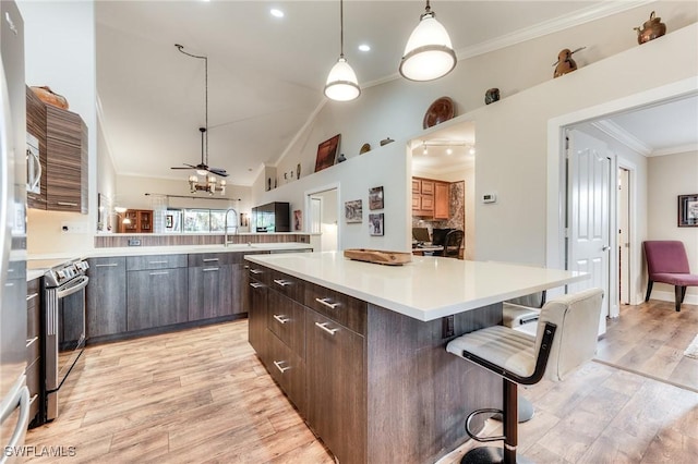 kitchen featuring ceiling fan, light countertops, light wood-style floors, crown molding, and a center island