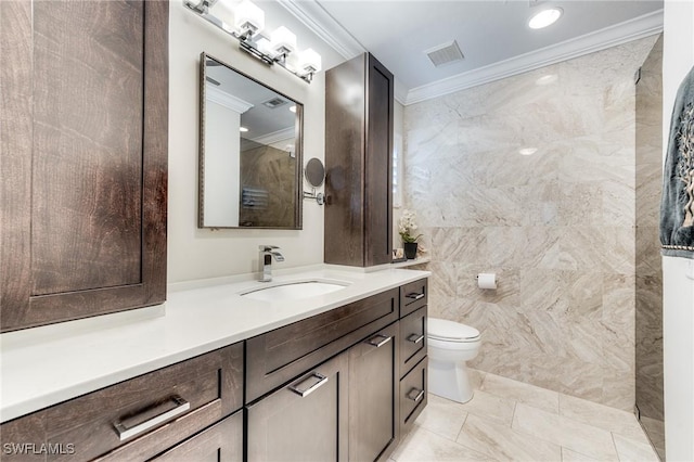 bathroom featuring visible vents, toilet, vanity, ornamental molding, and tile walls