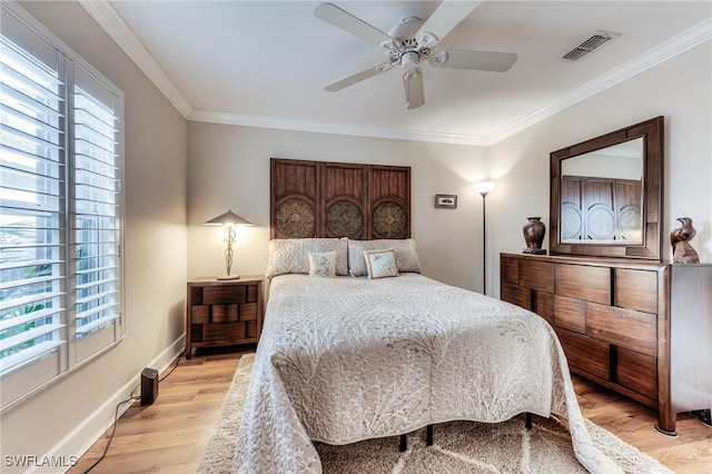 bedroom featuring crown molding, light wood-style flooring, multiple windows, and visible vents