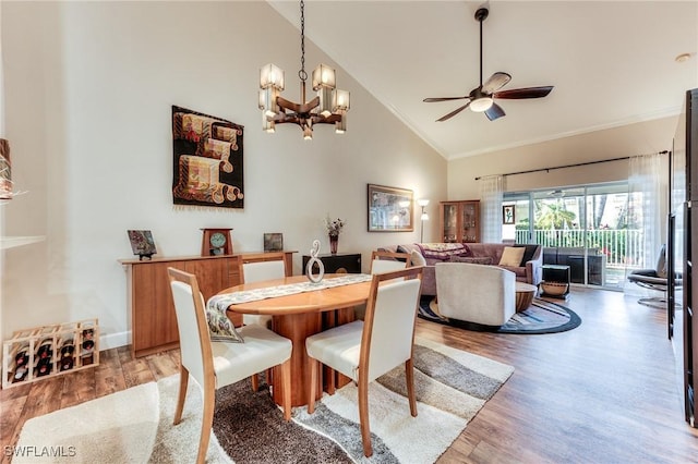 dining space featuring light wood-style floors, crown molding, high vaulted ceiling, and ceiling fan with notable chandelier