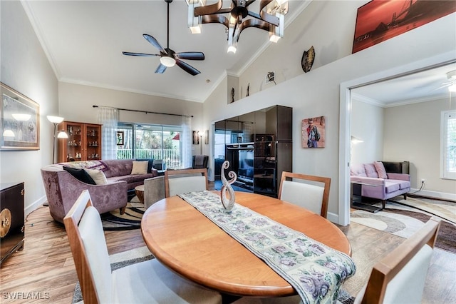 dining space with ceiling fan with notable chandelier, wood finished floors, baseboards, and ornamental molding