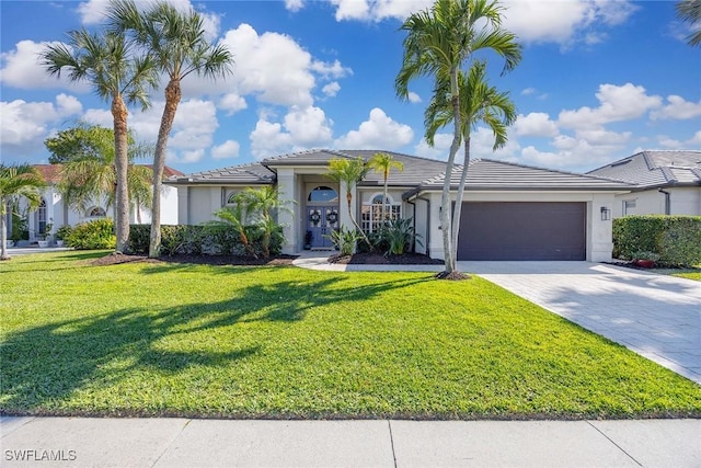 view of front of home featuring a front lawn, a tiled roof, stucco siding, decorative driveway, and an attached garage