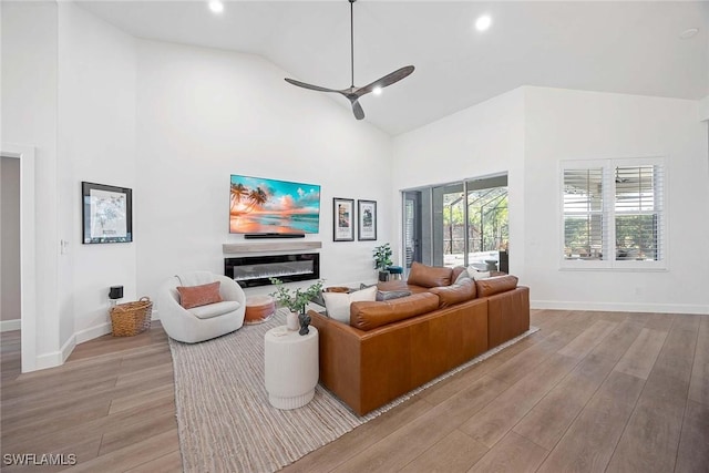 living area with light wood-style flooring, high vaulted ceiling, and ceiling fan