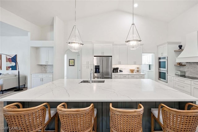 kitchen featuring custom range hood, a sink, a spacious island, white cabinetry, and appliances with stainless steel finishes