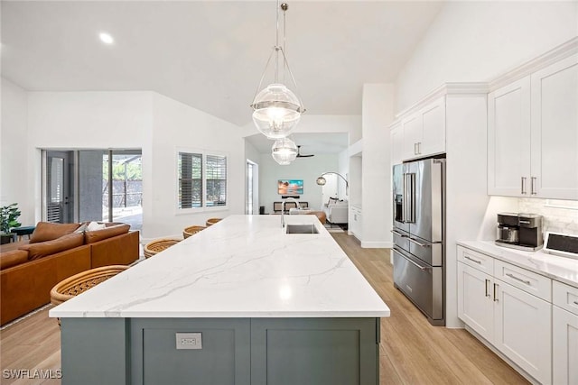 kitchen with an island with sink, a sink, open floor plan, white cabinetry, and high end refrigerator