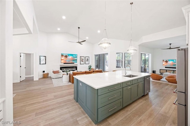 kitchen featuring open floor plan, light countertops, appliances with stainless steel finishes, a ceiling fan, and a sink