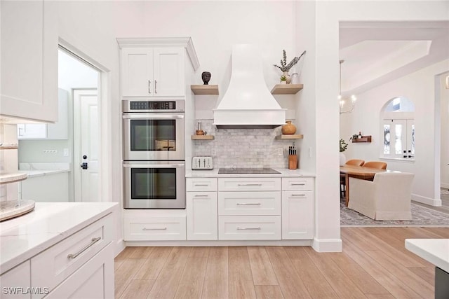 kitchen featuring premium range hood, open shelves, stainless steel double oven, white cabinets, and black electric stovetop