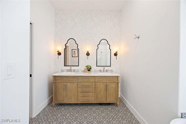 bathroom featuring double vanity, baseboards, and a sink