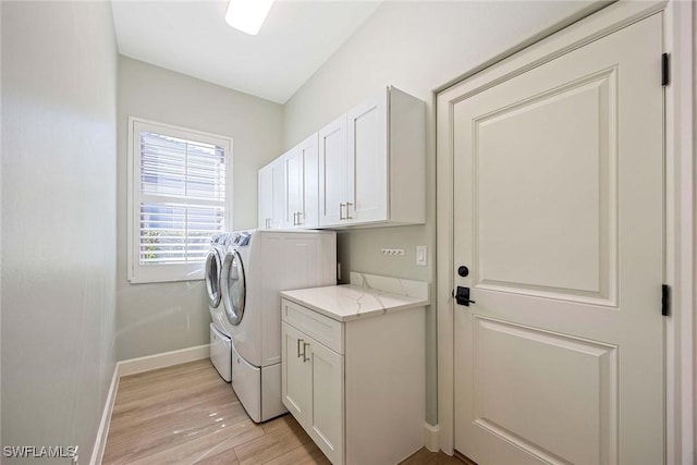 washroom with washer and dryer, light wood-type flooring, cabinet space, and baseboards