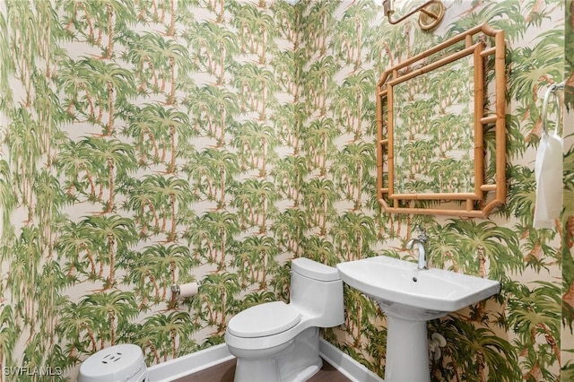 bathroom with baseboards, toilet, and wallpapered walls