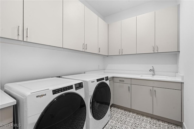 clothes washing area with cabinet space, separate washer and dryer, and a sink