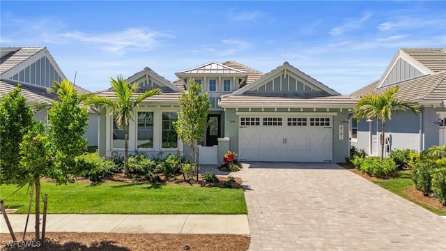 view of front facade featuring a tiled roof, a garage, decorative driveway, and stucco siding