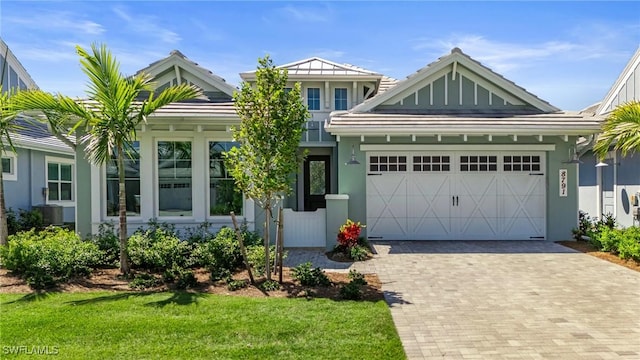 view of front of house with a garage, decorative driveway, a front lawn, and stucco siding