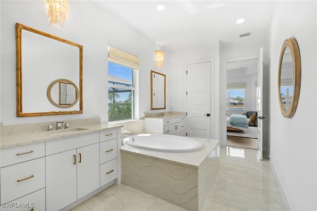 ensuite bathroom featuring visible vents, a garden tub, two vanities, marble finish floor, and a sink