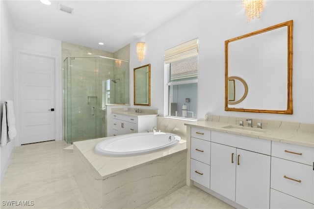 bathroom featuring a garden tub, two vanities, a stall shower, and a sink