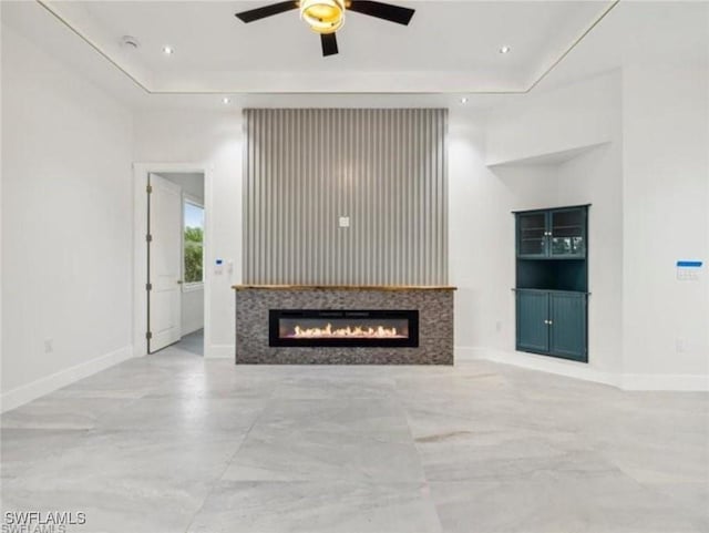 unfurnished living room with recessed lighting, baseboards, a raised ceiling, and a ceiling fan