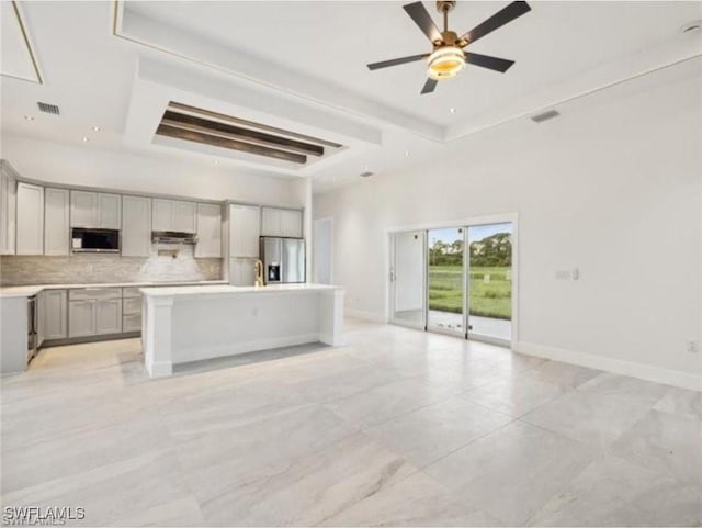 kitchen featuring visible vents, gray cabinets, open floor plan, stainless steel appliances, and a raised ceiling