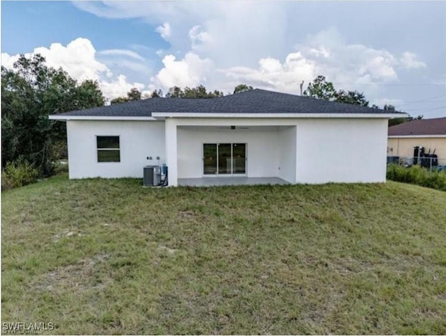 back of house with stucco siding, cooling unit, a yard, and roof with shingles