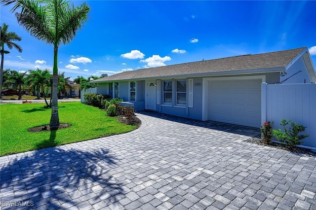 ranch-style home with fence, an attached garage, stucco siding, a front lawn, and decorative driveway