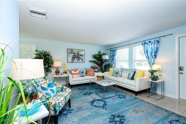 living room with tile patterned floors, visible vents, and a textured ceiling