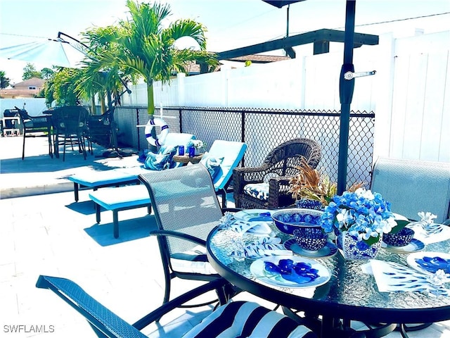 view of patio featuring outdoor dining area and fence