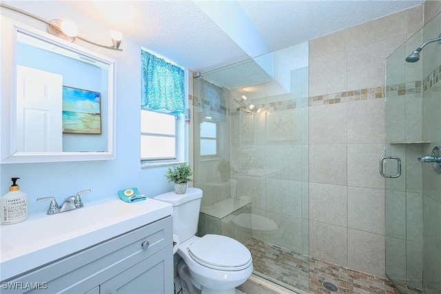 full bathroom with vanity, toilet, a shower stall, and a textured ceiling