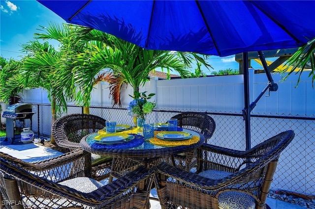 view of patio featuring outdoor dining space, fence, and grilling area