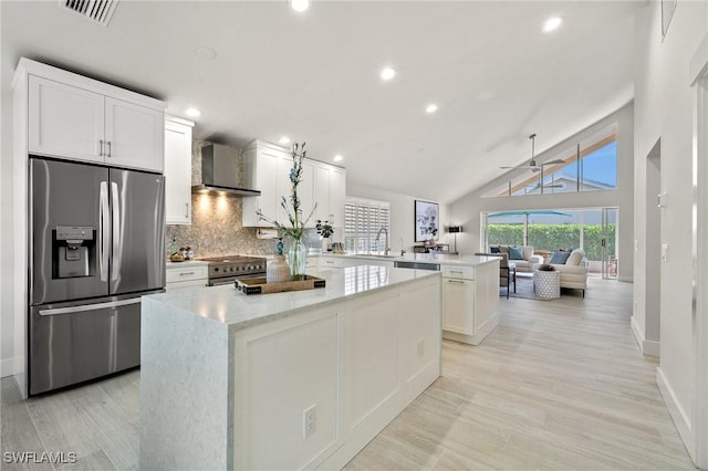 kitchen with a kitchen island, visible vents, a peninsula, stainless steel appliances, and wall chimney exhaust hood