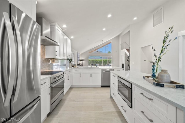 kitchen featuring visible vents, a peninsula, wall chimney exhaust hood, white cabinets, and appliances with stainless steel finishes