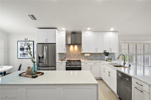 kitchen with appliances with stainless steel finishes, a sink, wall chimney exhaust hood, decorative backsplash, and visible vents