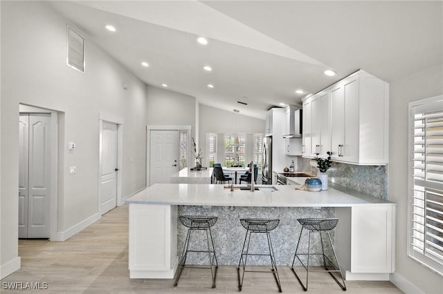 kitchen featuring a sink, light countertops, lofted ceiling, a kitchen bar, and visible vents